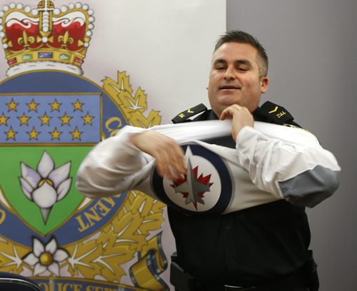 After updating the media on the latest arrests by Winnipeg Police in the city Thursday, Const. Jason Michalyshen puts on a Winnipeg Jets jersey showing the Police Service is supporting the team in the playoffs and asking fans to act responsibly. Wayne Glowacki/Winnipeg Free Press April 16  2015