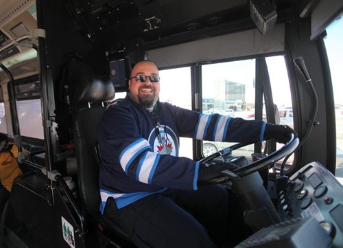 Transit bus driver Jason Scaletta is all smiles as he stops on Portage Ave. at Polo Park to drop off passengers wearing his Winnipeg Jets jersey.  He says his favourite player is Dustin Byfuglien.  Standup photo.   Ruth Bonneville / Winnipeg Free Press April 16, 2015