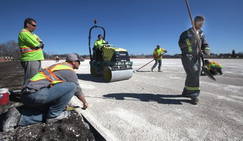 Chabot Enterprises forman Brett Tocher (kneeling left) and his crew of 9 put the final touches levelling a revamped "Shaughnessy" city soccer field betweeen Pacific and Alexander near Keewatin Friday afternoon.  See story. April 17, 2015 - (Phil Hossack / Winnipeg Free Press)
