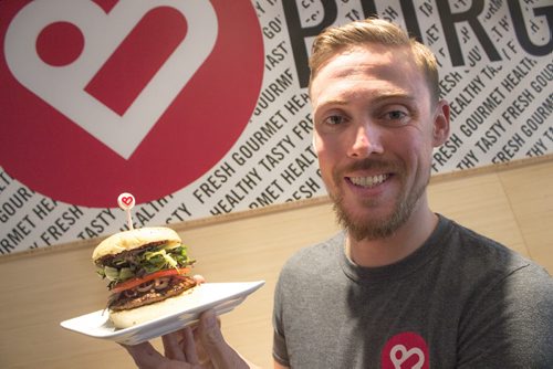 Marc Priestly, co-owner of Nuburger on Stafford Ave., holds up the healthy burger joint's latest creation, the Smak Shot. The new burger was made in honour of the Winnipeg Jets' playoff berth. (Jessica Botelho-Urbanski / Winnipeg Free Press)