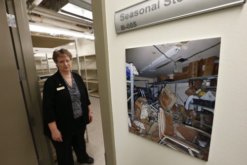Mary Knight, CEO for Golden Links Lodge in the renovated storage room in the basement by a photograph showing the damage to the storage area after the basement filled with water on April 20 2014. She gave the media a tour Wednesday of the completed renovations and up grades to the Lodge in St. Vital. Residents returned to their home this week. Kevin RollasonWayne Glowacki/Winnipeg Free Press April 22 2015