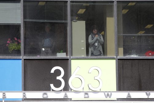 Haz Mat scene at 363 Broadway. A person on the second floor watches as the suspicious package gets dealt with. BORIS MINKEVICH/WINNIPEG FREE PRESS APRIL 23, 2015