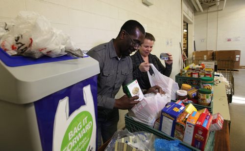 Patrick Fosu-Siaw and Tammy Watson with Winnipeg Harvest ,happily fill gently used plastic bags that have been donated to Wpg. Harvest for starter kits of food.  Using recycled bags eliminates buying thousands of new bags that could end up in the landfill.    Ruth Bonneville / Winnipeg Free Press April 23, 2015