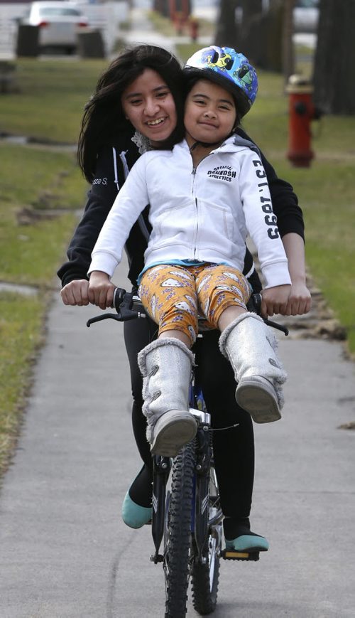 Charisse Salud gives her younger sister Ariam Leira a ride through their Boyd Ave. neighbourhood on a warm Friday afternoon. Wayne Glowacki / Winnipeg Free Press April 24 2015