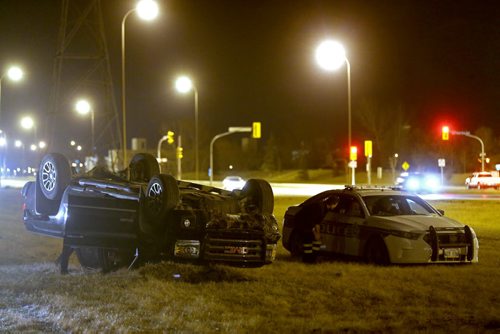 A tow truck driver speaks with Police at the scene where a truck rolled over in the grass along Bishop Grandin near Lakewood Blvd, late Friday, April 24, 2015. (TREVOR HAGAN/WINNIPEG FREE PRESS)