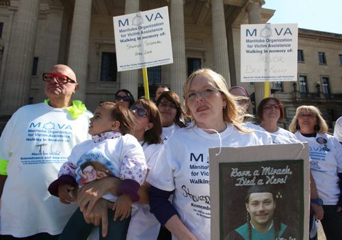 Debra Vallier (front, blond) holds a picture of her son - Steven Dodge in front of the Leg Saturday with fellow citizens rallying for victim services offered by  MOVA (Manitoba Organization for Victim Assistance), which supports co-victims of homicide.  MOVA held a walk and small rally at the Leg Saturday in remembrance of these homicide victims like Vallier's son who was stabbed to death.    Standup photo   Ruth Bonneville / Winnipeg Free Press April 25, 2015