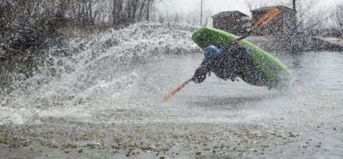 150426 DAVID LIPNOWSKI / WINNIPEG FREE PRESS  Steven Walker of the Manitoba Whitewater Club performs tricks in his kayak after sliding down the toboggan slide Sunday April 26, 2015 at FortWhyte Alive for the Earth Day Celebration.