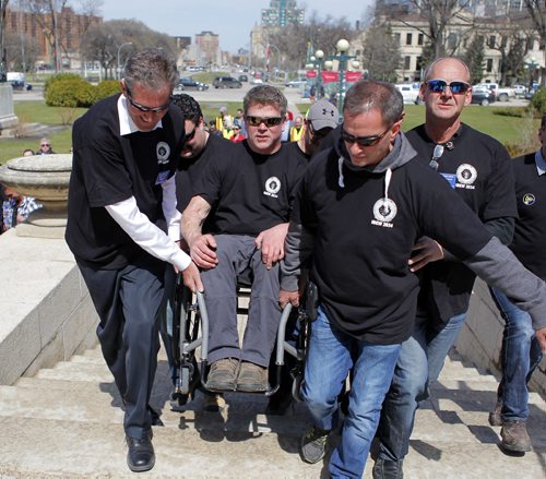 Day of Mourning Leaders Walk. SAFE Workers of Tomorrow Leaders Walk participants gathered at Union Centre, 275 Broadway, and marched down to the Manitoba Legislative Building. There a media event at the Manitoba Legislative Building commenced. In this photo left-Leader of the Opposition of the Manitoba Legislative Assembly Brian Pallister helps a union member Danny Fletcher (in wheelchair) get up the front of the leg.  BORIS MINKEVICH/WINNIPEG FREE PRESS APRIL 28, 2015
