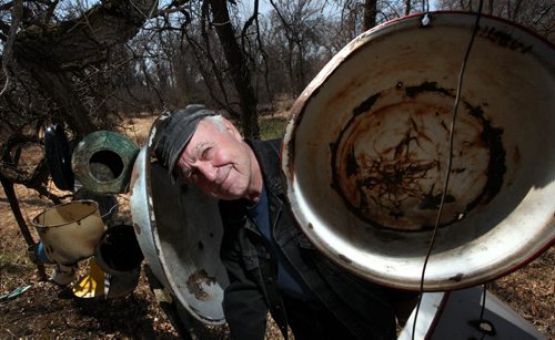 Real Berard poses among old enameled pans that form a "wind chime" at his restored log cabin retreat near St Pierre. He's an artist, canoe route mapper, and political cartoonist. See Bill Redekop's story. April 29, 2015 - (Phil Hossack / Winnipeg Free Press)