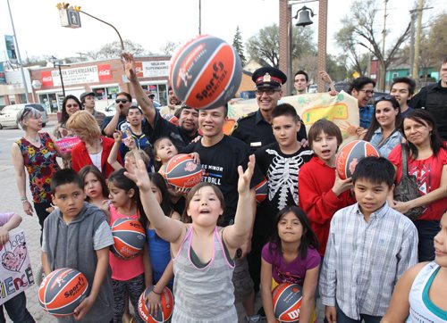 Lenard Monkman, under ball surrounded by kids and community leaders at the Bell Tower on Selkirk Ave Friday Night- Monkman handed out 10 basketballs to children to promote  his launch of 100 balls campaign by Aboriginal Youth Opportunities- He is planning a family fun day on May 31 featuring a basketball game between the Neechi Commons All-stars vs the Winnipeg Police including police Chife Devon Clunis-See Carol Sanders story- May 01 , 2015   (JOE BRYKSA / WINNIPEG FREE PRESS)