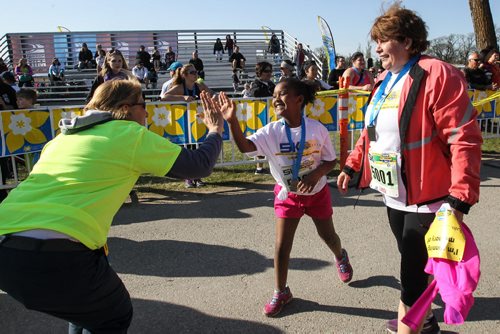 Amy McClusky, 8, gives Karen Timchuk, a cancer survivor, a high-five after crossing the finish line with her mom, Linda (right) during the Winnipeg Police Half-Marathon at Assiniboine Park Sunday morning. 150503 - Sunday, May 03, 2015 -  (MIKE DEAL / WINNIPEG FREE PRESS)