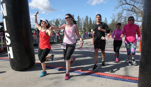 Fern McIver (left) and Joanne Schiewe (second from left) cross the finish line during the Winnipeg Police Half-Marathon at Assiniboine Park Sunday morning. Joanne was diagnosed three months ago to the day with brain cancer. 150503 - Sunday, May 03, 2015 -  (MIKE DEAL / WINNIPEG FREE PRESS)