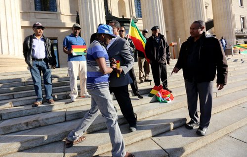 A man who had been carrying an Oromia flag is removed by Members of the Ethiopian community who had gathered at the Manitoba Legislative Building to hold a vigil and ceremony mourning Ethiopians who have been killed and persecuted in recent weeks in African countries and around the world, Sunday, May 3, 2015. (TREVOR HAGAN/WINNIPEG FREE PRESS)