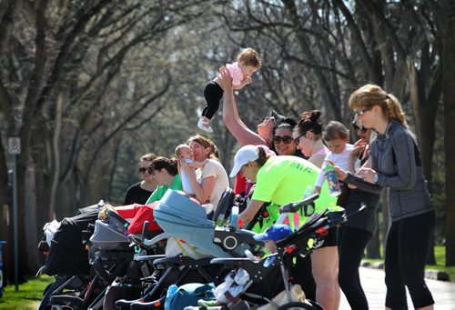 Danica Benson holds 7-month-old Larkyn way up high as she plays with her along with the other moms during a short break in the stroller training workout at Assinibone Park. 

49.8 Certified post and pre natal trainer, Cindy Miller (front of crowd, red hair with pony tail) hosts workout sessions for new moms at Assiniboine park recently.  Classes last 45 - 50 minutes - moms walk vigorously for 5 minutes with their strollers, then pause to do lunges, step-ups, etc. for 5 minutes, then walk again, stop again until meeting back at the starting point, the pavilion, to do a cool down stretch.    See story Dave Sanderson's story. May 01, 2015 Ruth Bonneville / Winnipeg Free Press