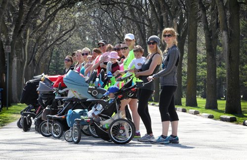 Moms line up together for a quick group photo during a short break in training (trainer, CIndy Miller is at front of the line).  See below for more info.  

49.8 Certified post and pre natal trainer, Cindy Miller (front of crowd, red hair with pony tail) hosts workout sessions for new moms at Assiniboine park recently.  Classes last 45 - 50 minutes - moms walk vigorously for 5 minutes with their strollers, then pause to do lunges, step-ups, etc. for 5 minutes, then walk again, stop again until meeting back at the starting point, the pavilion, to do a cool down stretch.    See story Dave Sanderson's story. May 01, 2015 Ruth Bonneville / Winnipeg Free Press