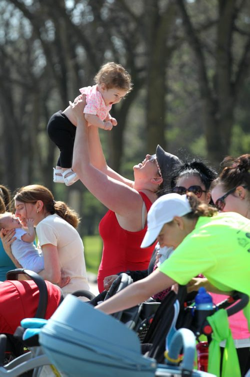 Danica Benson plays with 7-month-old Larkyn during a break in the stroller training workout at Assinibone Park. 

49.8 Certified post and pre natal trainer, Cindy Miller (front of crowd, red hair with pony tail) hosts workout sessions for new moms at Assiniboine park recently.  Classes last 45 - 50 minutes - moms walk vigorously for 5 minutes with their strollers, then pause to do lunges, step-ups, etc. for 5 minutes, then walk again, stop again until meeting back at the starting point, the pavilion, to do a cool down stretch.    See story Dave Sanderson's story. May 01, 2015 Ruth Bonneville / Winnipeg Free Press
