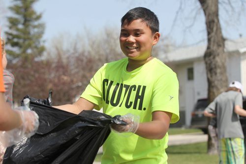 JR Baquino, a grade 7 student from Bernie Wolfe School opens his garbage bag for a fellow student as his classmates headed into their neighbourhood of Transcona to do some spring cleaning Tuesday.  They were one school of several in the area participating in this event including Arthur Day Middle School, Calvin Christian Collegiate and many others who spread themselves out across Transcona to pick up litter and collect recyclables.  Standup photo   May 05, 2015 Ruth Bonneville / Winnipeg Free Press