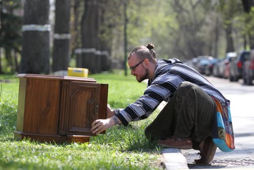 Rue Eldertree checks out a octagon cabinet sitting on a curb in Wolsely Saturday for the free weekend giveaway event that is on this weekend.   May 09, 2015 Ruth Bonneville / Winnipeg Free Press