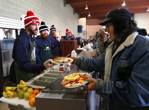 From left, Winnipeg Goldeyes pitchers Nick Hernandez and Coby Cowgill  help out serving a hearty breakfast at Agape Table Monday morning to guests including Bruce Jamieson. This is the second year the Goldeyes team have helped to volunteer with a breakfast and they also passed out free tickets to ball games.   Wayne Glowacki / Winnipeg Free Press May 11  2015