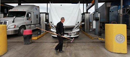 Andre LaPalme cleans the glass while he tops up the saddle tanks on his rig in Winnipeg Tuesday. He's headed to the mid west USA from Montreal. See story re: fuel prices. May 12, 2015 - (Phil Hossack / Winnipeg Free Press)