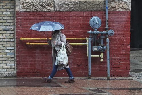 A pedestrian walks along Arthur Street Thursday during a steady drizzle of rain.  150514 May 14, 2015 Mike Deal / Winnipeg Free Press