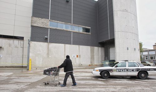 A person pushes their belongings past the taped-off loading dock at the Manitoba Museum Monday morning.  150518 May 18, 2015 Mike Deal / Winnipeg Free Press