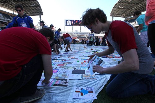Grant Kroeker a Grade eleven student  from Vincent Massey School in the Pembina Trails School Division places his artwork on a  huge tarp-like panel in the shape of the United Nations symbol along with thousands of other students from the division at Investors Group Field Wednesday.  All the artwork from the 13,000 students in the Pembina Trails Division will form the UN shape that will fill the grounds of the Investors Group Field over the coming days  in recognition of the human rights of children everywhere. Standup photo  May 20, 2015 Ruth Bonneville / Winnipeg Free Press