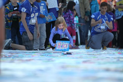 A young girl from Whyte Ridge School in the Pembina Trails School Division, gets ready to place her artwork field on a huge tarp-like panel in the shape of the United Nations symbolat Investors Group Stadium Wednesday. All the artwork from the 13,000 students in the Pembina Trails Division will form the UN symbol that will fill the grounds of the Investors Group Field over the coming days  in recognition of the human rights of children everywhere. Standup photo  May 20, 2015 Ruth Bonneville / Winnipeg Free Press
