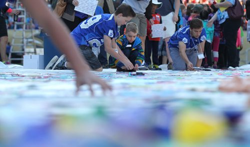 A young boy from Whyte Ridge School in the Pembina Trails School Division, gets ready to place her artwork field on a huge tarp-like panel in the shape of the United Nations symbolat Investors Group Stadium Wednesday. All the artwork from the 13,000 students in the Pembina Trails Division will form the UN symbol that will fill the grounds of the Investors Group Field over the coming days  in recognition of the human rights of children everywhere. Standup photo  May 20, 2015 Ruth Bonneville / Winnipeg Free Press