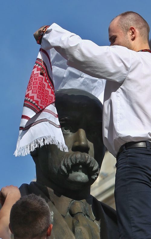 Ivan Marynovskyy (left) and Oleg Azovsky (right) attempt to put a Rushnyk or ritual cloth around the neck of the Taras Shevchenko statue on the grounds of the Manitoba Legislative building Thursday evening as they celebrate Vishivanka Day. The Winnipeg Ukrainian community is gathered at the statue before heading to The Forks and the Manitoba Theatre for Young People where the Ukrainian Kino Film Festival is taking place. Vishivanka Day is an opportunity to celebrate and promote Ukrainian culture; many approximately fifty participants wore their intricately embroidered Vishivanka shirts.  150521 May 21, 2015 Mike Deal / Winnipeg Free Press