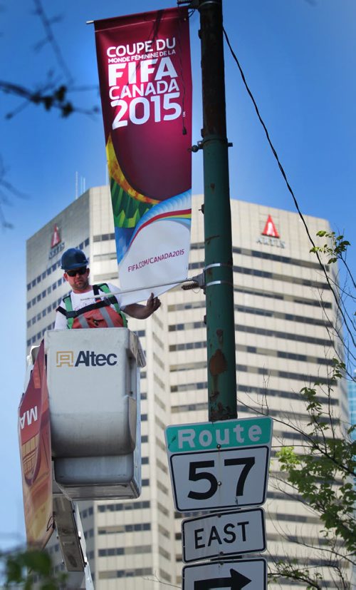Joel Kubay hangs FIFA banners along Main Street downtown Friday morning. THe international Women's World cup makes an appearance in the city net month. See release. STAND-UP.  May 22, 2015 - (Phil Hossack / Winnipeg Free Press)