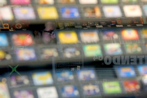 A spectator is seen off the reflection on a display of games for sale as people crowd into PNP Games on Portage Avenue for a Super Smash Bros. tournament, Sunday, May 24, 2015. (TREVOR HAGAN/WINNIPEG FREE PRESS)