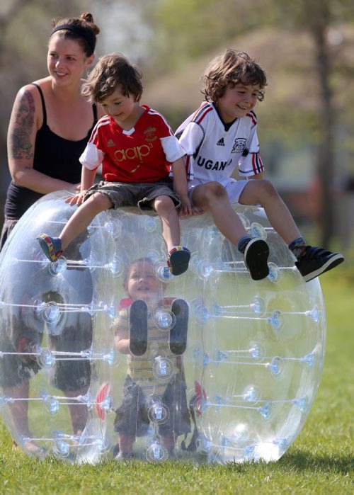 Samantha Phelps, with her children, Zebediah, 15mo, Elijah, 4, and Leonardo, 7. Neil Trudeau runs River City Bubble Ball, a company that organizes bubble soccer, Saturday, May 23, 2015. (TREVOR HAGAN/WINNIPEG FREE PRESS) - for dave sanderson intersection 49.9 piece