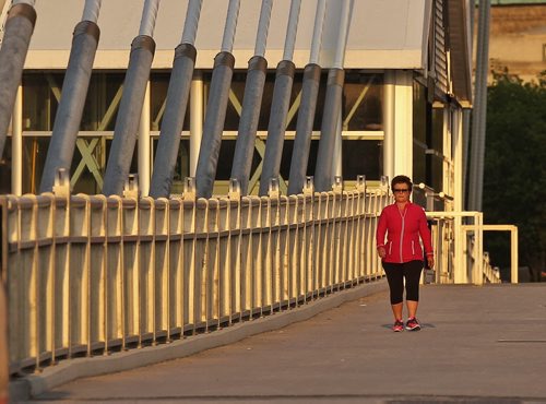 A pedestrian makes their way across a golden Esplanade Riel as it is lit by the early morning sun Wednesday.  150527 May 27, 2015 Mike Deal / Winnipeg Free Press