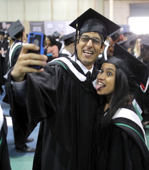 University of Manitoba convocation. Before the actual convocation that starts at 3pm grads took photos with friends and family. Commerce grads left-right Vishal Guliani and Shalaka Godse do a selfie in the Max Bell field house before the grad starts. That is where they stage before they go in. Both have jobs and graduated in the honours program of the Asper School of Business. BORIS MINKEVICH/WINNIPEG FREE PRESS May 27, 2015