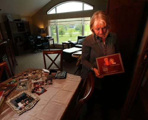 Standing besidet her dining room table covered in snapshots, Joanne Rislund  embraces an urn containing her father Frank Alexander's ashes as she recalls memories good and bad aboiut him. An Alziemer's patient he was killed by another senior in a Winnipeg Nursing home. See Carol Sanders post enquiry story. May 28, 2015 - (Phil Hossack / Winnipeg Free Press)
