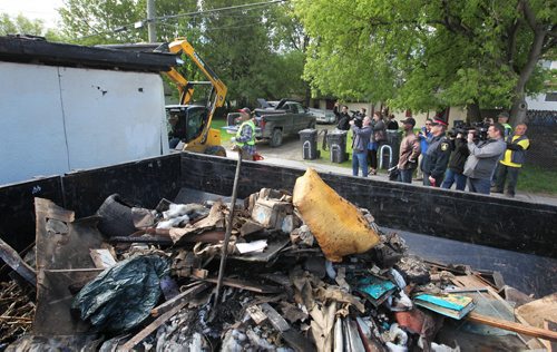 Police Chief Devon Clunis (right, brown jacket, hat) stands with members of the media as they watch a bulldozer tear down a garage in the backlane behind Selkirk Ave. that was destroyed by fire, as a part of the -  Restore Our Core initiative taking place this weekend. The event is supported by the Wpg Police Service, Love Winnipeg and concerned citizens and business leaders to create safer, cleaner and stronger communities in all areas of the city including the core and North End.    May 29, 2015 Ruth Bonneville / Winnipeg Free Press