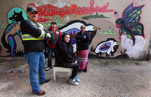 Left to right, James Favel, Blackwolf Hart, Jackie Traverse and Cheryl James pose in front of a mural Jackie helped create. See Alex Paul's story. May 29, 2015 - (Phil Hossack / WInnipeg Free Press)  Jackie Traverse, aunt of Shanastene McLeod, the woman the drummers and marchers were searching to find.  James Favel, council member of the Bear Clan patrol.  Cheryl James, drummer with the north end womens drum group. Please ask her how to spell the name of her group. Its in Ojibway and I dont have it handy. (Keewatin Otchitchak Drumgroup)  Blackwolf Hart, another drummer who is a member of the tiny local chapter of the American Indian Movement in Winnipeg, along with Jackie. (there are like three initiated members so its very small.)  (Keewatin Otchitchak Drumgroup)