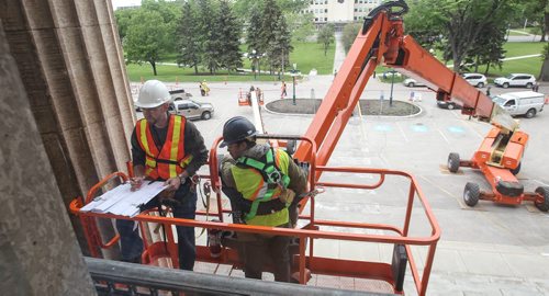 Michael Scott (white hardhat), a heritage architect with Charles Hazell Associates and Larry Gibson (blue hardhat) with Total Co-ordination construction examine the tyndall stone structure of the legislative building gathering data for upcoming repairs. 150602 - Tuesday, June 02, 2015 -  MIKE DEAL / WINNIPEG FREE PRESS