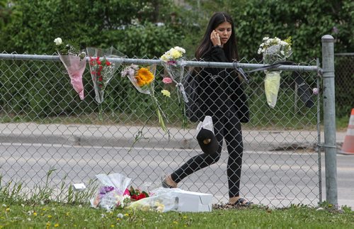 Students walk past a memorial of flowers set up outside the doors to Kelvin High School Wednesday the day close to where former student Brett Bourne was stabbed. Bourne died in hospital from his injuries. 150603 - Wednesday, June 03, 2015 -  MIKE DEAL / WINNIPEG FREE PRESS
