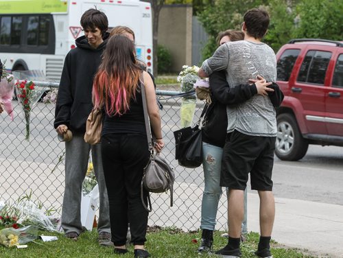 Students hug as they gather briefly amongst a memorial of flowers set up outside the doors to Kelvin High School Wednesday the day close to where former student Brett Bourne was stabbed. Bourne died in hospital from his injuries. 150603 - Wednesday, June 03, 2015 -  MIKE DEAL / WINNIPEG FREE PRESS