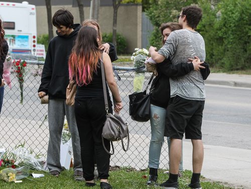 Students hug as they gather briefly amongst a memorial of flowers set up outside the doors to Kelvin High School Wednesday the day close to where former student Brett Bourne was stabbed. Bourne died in hospital from his injuries. 150603 - Wednesday, June 03, 2015 -  MIKE DEAL / WINNIPEG FREE PRESS