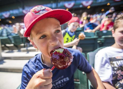 Tyler Smith, 13, bites into a candy apple while watching a Goldeyes game at Shaw Park on Thursday, June 4, 2015.  Mikaela MacKenzie / Winnipeg Free Press