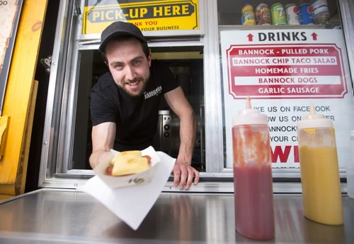 Anthony Faraci, owner of the Bannock Factory Food Trailer, hands two bannock dogs to a customer on Friday, June 5, 2015. Mikaela MacKenzie / Winnipeg Free Press