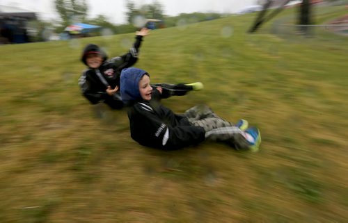 Jackson Michaleski, 9, and his brother, Matthew, 6, sliding down a slippery hill while watching MSHAA Provincial Track and Field Championships during heavy rain, at University Stadium at the University of Manitoba, Saturday, June 6, 2015. (TREVOR HAGAN/WINNIPEG FREE PRESS)