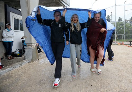 Bobbee Morrisseu, 16, Aislyn Balak, 17, and Kailee Evans, 15, use a tarp for shelter during the MSHAA Provincial Track and Field Championships during heavy rain, at University Stadium at the University of Manitoba, Saturday, June 6, 2015. (TREVOR HAGAN/WINNIPEG FREE PRESS)