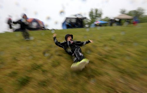 Jackson Michaleski, 9, right, and his brother, Matthew, 6, sliding down a slippery hill while watching MSHAA Provincial Track and Field Championships during heavy rain, at University Stadium at the University of Manitoba, Saturday, June 6, 2015. (TREVOR HAGAN/WINNIPEG FREE PRESS)