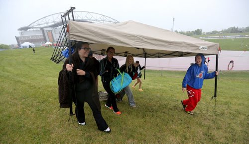 Spectators carry a tent to stay dry during MSHAA Provincial Track and Field Championships during heavy rain, at University Stadium at the University of Manitoba, Saturday, June 6, 2015. (TREVOR HAGAN/WINNIPEG FREE PRESS)