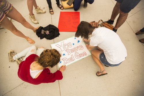 Talitha Kaethler (left) and Emily Wuest, cousins from Winnipeg and Kansas, draw signs while waiting in line to see the Nigeria vs. Sweden game at the Investors Group Field on Monday, June 8, 2015. Mikaela MacKenzie / Winnipeg Free Press