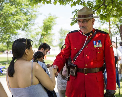 Rob Lockhart, RCMP officer, shakes hands with First Nations people as they wait in line wait in line to receive their treaty cheques at the Forks in Winnipeg on Tuesday, June 9, 2015. Mikaela MacKenzie / Winnipeg Free Press